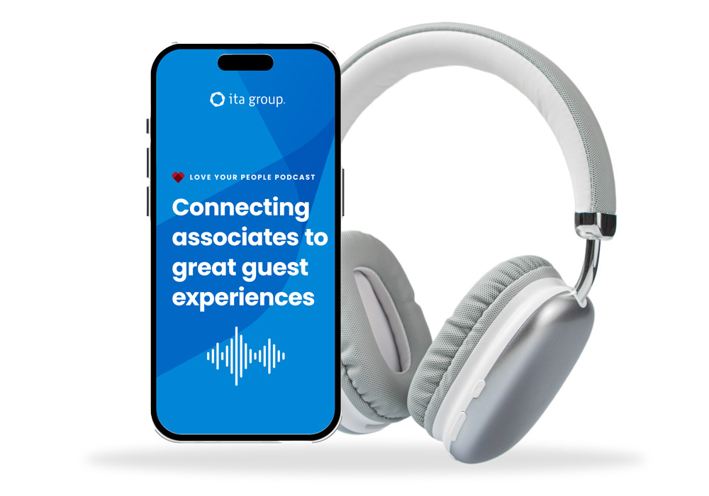 Image of mobile device playing ITA Group's podcast Connecting associates to great guest experiences, next to a set of headphones